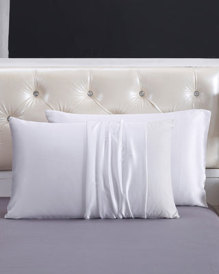 a bed with white sheets and pillows on it