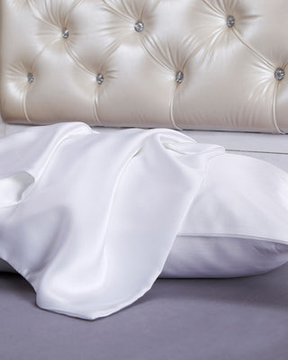 a bed with a white comforter and pillows