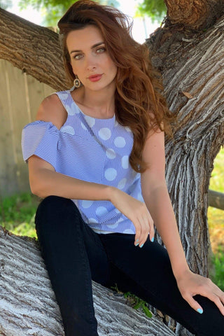 a woman sitting in a tree wearing a blue and white striped top