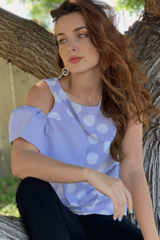 a woman sitting in a tree wearing a blue and white striped top