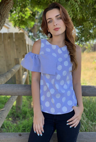 a woman wearing a blue and white polka print top