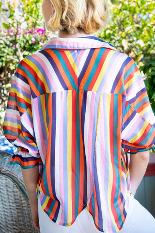 a woman wearing a colorful striped shirt and white jeans