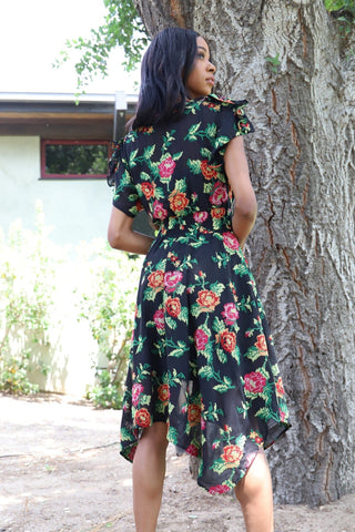 a woman standing in front of a tree wearing a floral dress