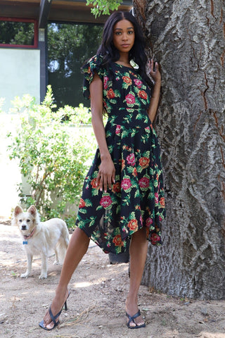 a woman standing next to a tree with her dog