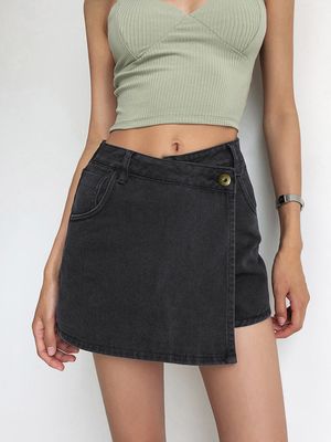 a woman wearing a green crop top and black denim skirt