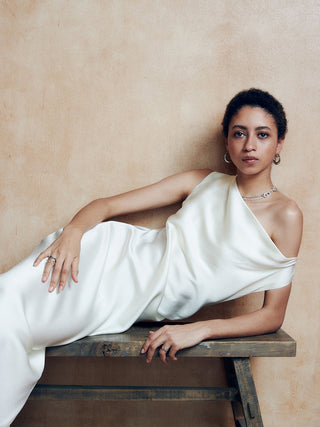 a woman in a white dress sitting on a wooden bench