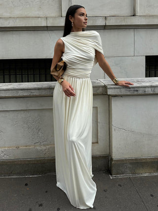 a woman in a white dress standing on a sidewalk