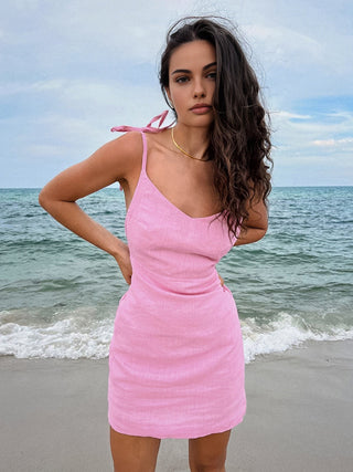 a woman in a pink dress on the beach