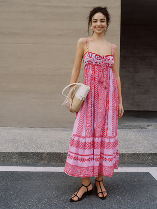 a woman in a pink dress standing in front of a wall