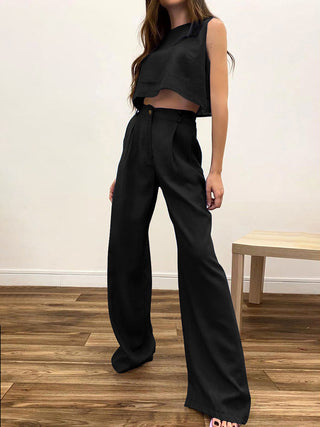 a woman wearing a black crop top and wide pants