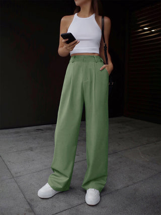 a woman in a white tank top and green pants