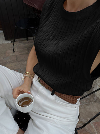 a woman sitting on a chair holding a cup of coffee