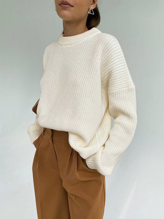 a woman wearing a white sweater and brown pants