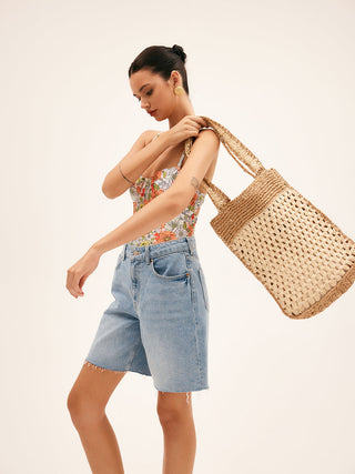 a woman in a floral top is carrying a woven bag