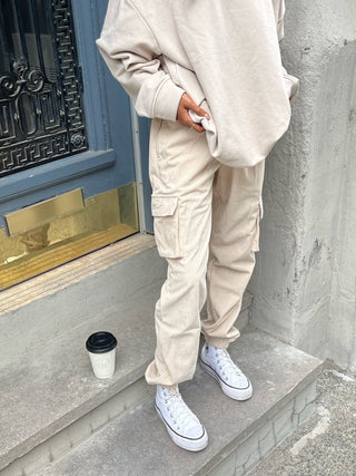 a woman wearing a beige sweatshirt and cargo pants