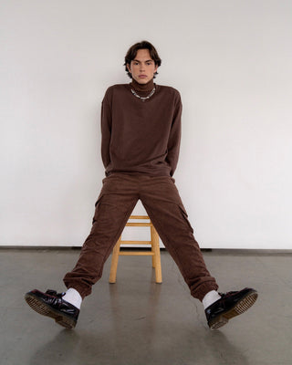 a young man sitting on a chair with his legs crossed