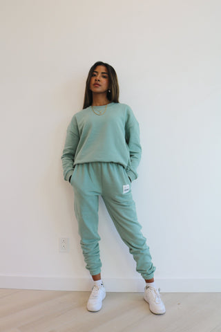 a woman wearing a green sweatshirt and sweat pants