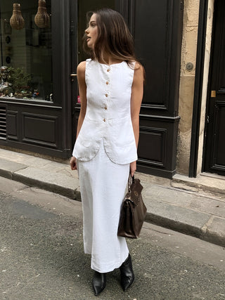 a woman in a white dress is walking down the street