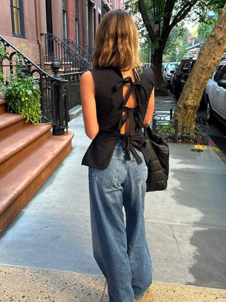 a woman standing on the sidewalk with her back turned