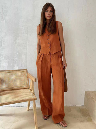 a woman standing in front of a white wall wearing an orange jumpsuit