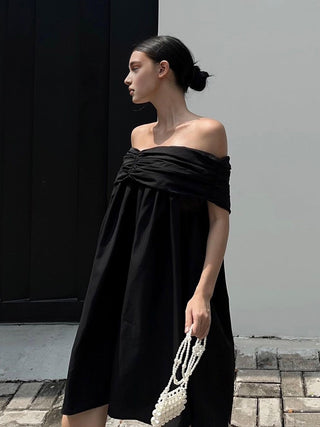 a woman wearing a black off the shoulder dress