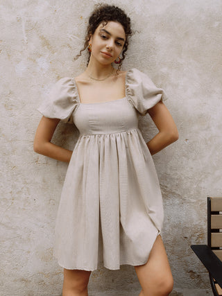 a woman in a dress leaning against a wall