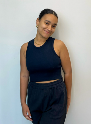 a woman wearing a black crop top and black pants