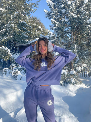 a woman wearing a purple sweatshirt and sweat pants in the snow