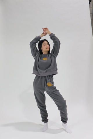 a young girl wearing a grey sweatshirt and sweat pants