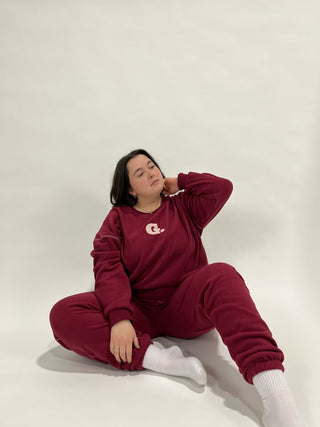 a woman sitting on the floor wearing a maroon sweatshirt and white socks