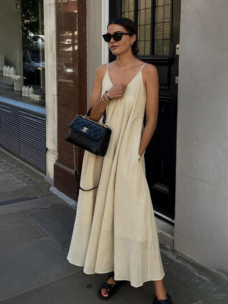 a woman in a white dress is standing on the sidewalk