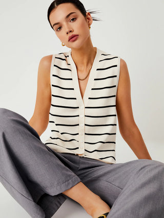 a woman sitting on the floor wearing a white and black striped top