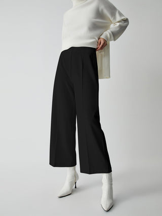 a woman in a white sweater and black pants