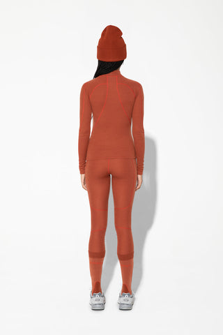 the back view of a woman in an orange long - sleeved top and leggings