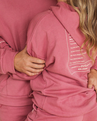 a woman in a pink hoodie holding a cell