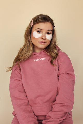 a young girl wearing a pink sweatshirt with a white eye patch on her cheek