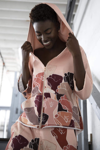 a woman in a pink hoodie is holding a cell