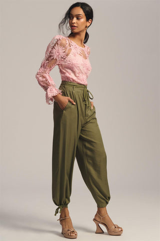 a woman in a pink top and green pants