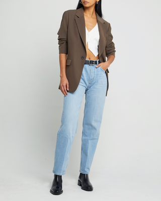 a woman wearing a brown blazer jacket and jeans