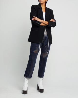 a woman wearing a black blazer jacket and jeans