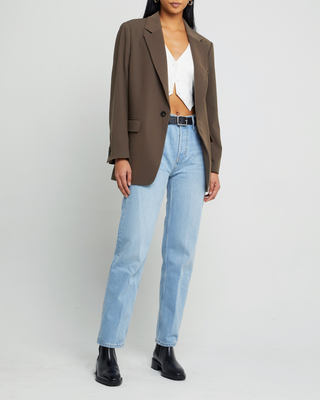 a woman wearing a brown blazer jacket and jeans