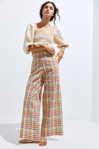 a woman in a white top and colorful plaid pants