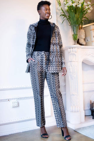 a woman standing in front of a fireplace wearing leopard print trousers