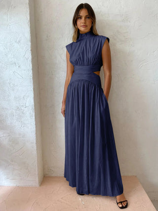 a woman in a blue dress standing against a wall