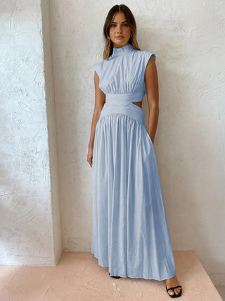 a woman in a blue dress standing against a white wall