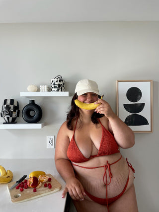 a woman in a red bikini holding a banana