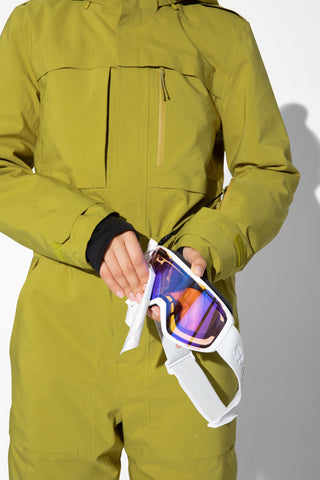 a man in a green suit holding a pair of ski goggles