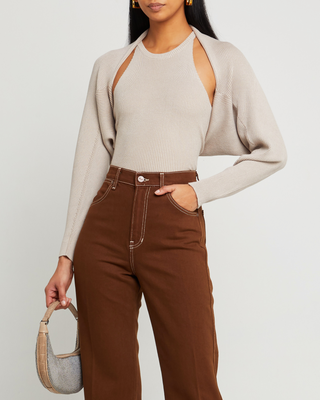 a woman in a beige sweater and brown pants