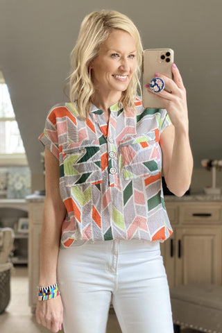 a woman wearing a colorful shirt and white jeans