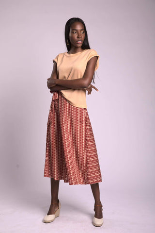 a woman in a beige top and red skirt